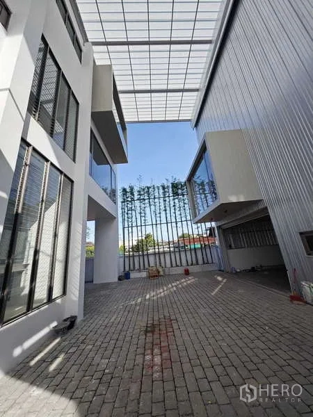 Home Office for rent or sale - Paved courtyard between buildings under a translucent canopy roof.