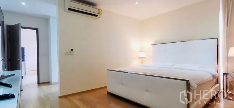 公寓 出租或出售在Watthana, Bangkok - 主卧宽敞，木地板，软包大床与床头灯营造温馨。