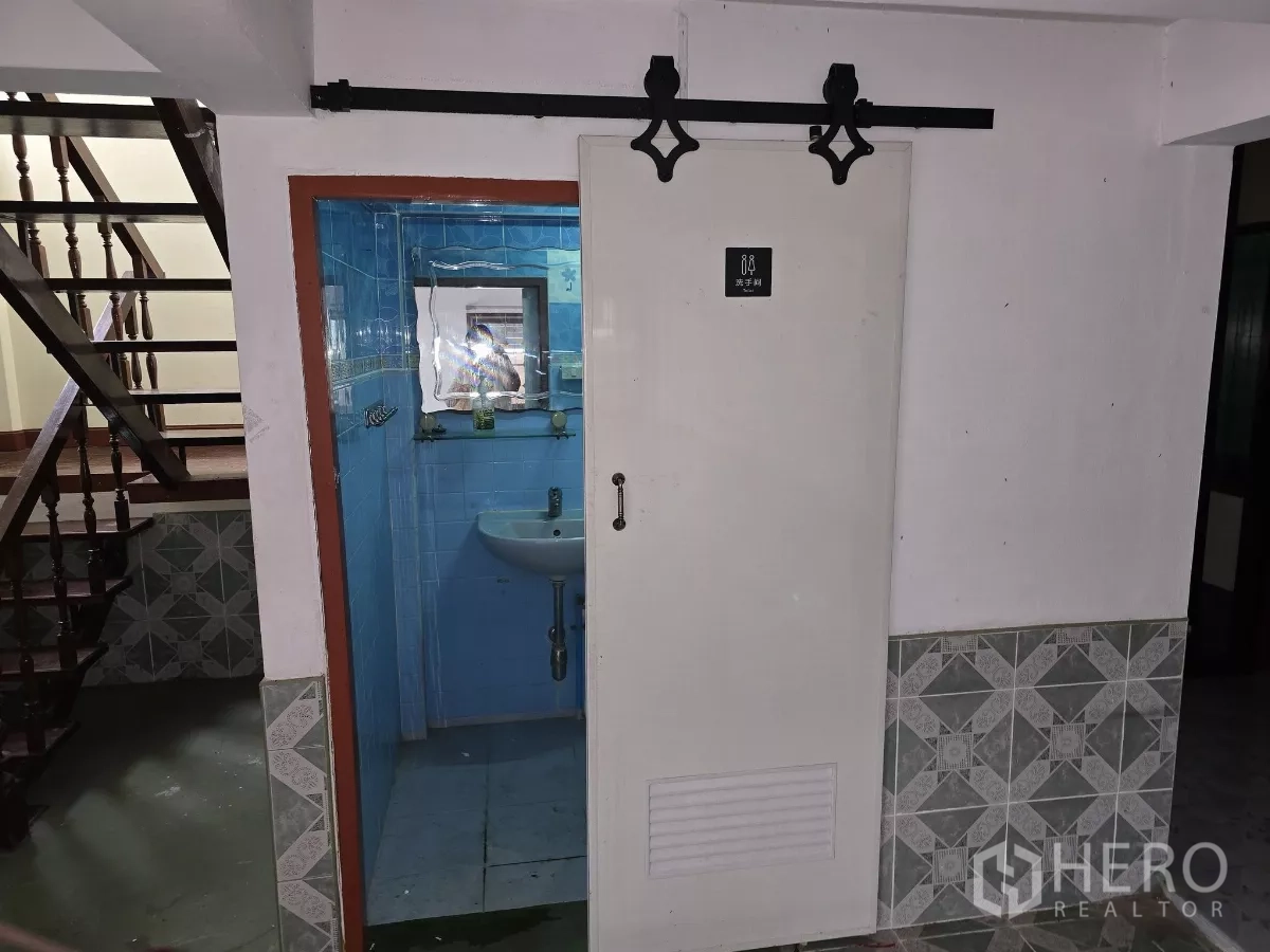 带办公室的家 出租在Wang Thonglang, Bangkok - 一层卫生间，蓝色瓷砖与洗手盆，位于楼梯旁的推拉门内