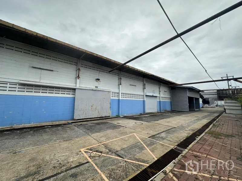 工厂 出售在Khlong Luang, Pathum Thani - 仓库外墙一侧，设装卸门与带顶棚的服务通道。