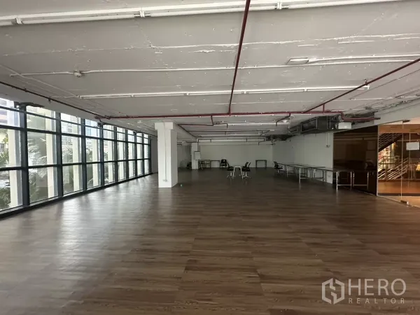 Retail Space for rent - Bright retail hall with long window wall, wood-look floors and structural columns.