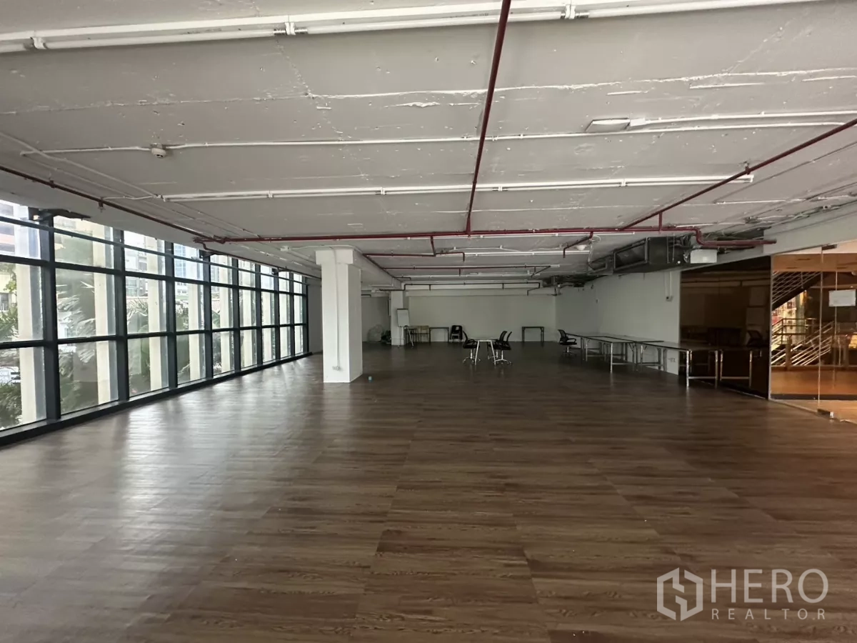 Retail Space for rent - Bright retail hall with long window wall, wood-look floors and structural columns.