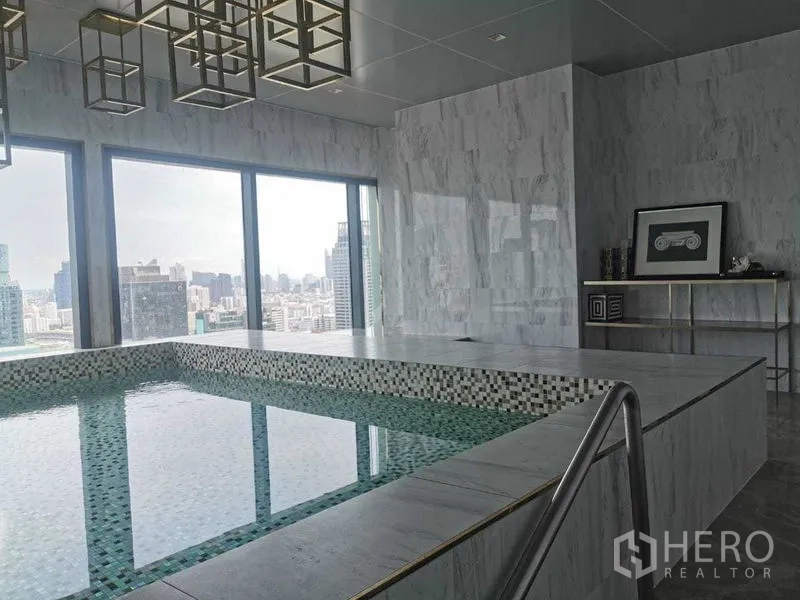 Condominium for rent in Ratchathewi, Bangkok - Indoor marble plunge pool with large windows and a city view.