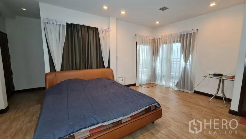 Detached House for rent in Saphan Sung, Bangkok - Large master bedroom with balcony doors and wood-look flooring.