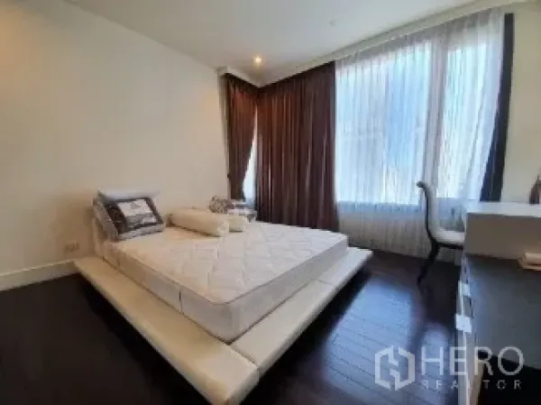 公寓 出售 - 主卧配平台床，深色木地板与大窗帘窗户。