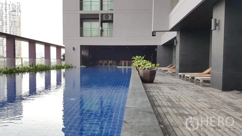 Condominium for rent in Khlong Toei, Bangkok - Elevated lap pool with deck chairs and urban views at the condominium.
