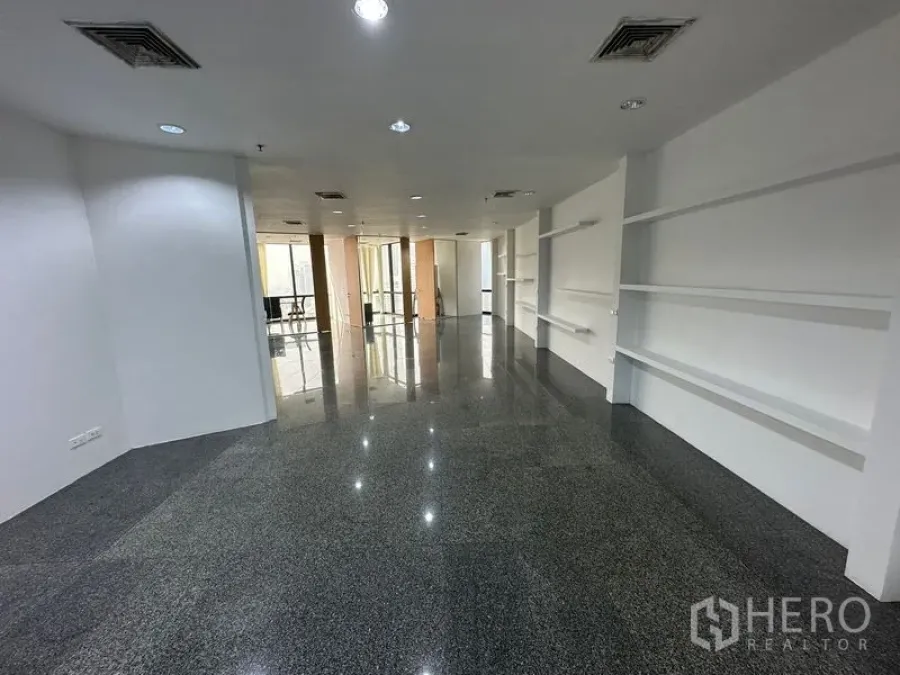 Office Space for rent - Open workspace with dark stone flooring, downlights and display shelving leading to meeting rooms.