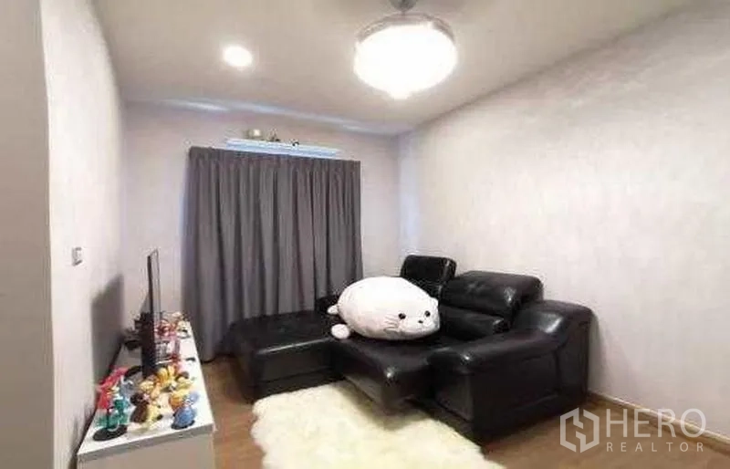 Detached House for sale in Bang Phli, Samut Prakan - Cozy family room with black leather sectional, TV console and grey curtains in a Bang Phli home.