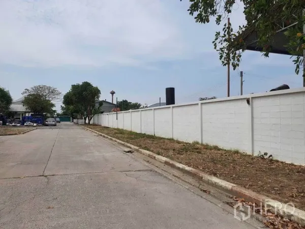 Warehouse for rent in Nakhon Pathom - Internal road with long white boundary wall in a secure industrial compound.