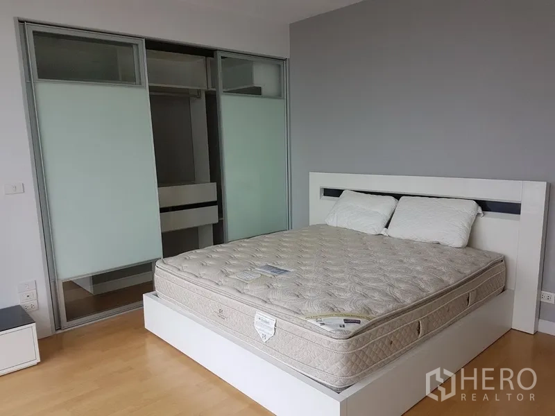Condominium for rent in Khlong Toei, Bangkok - Second bedroom featuring a queen bed and built-in wardrobe with frosted sliding doors.
