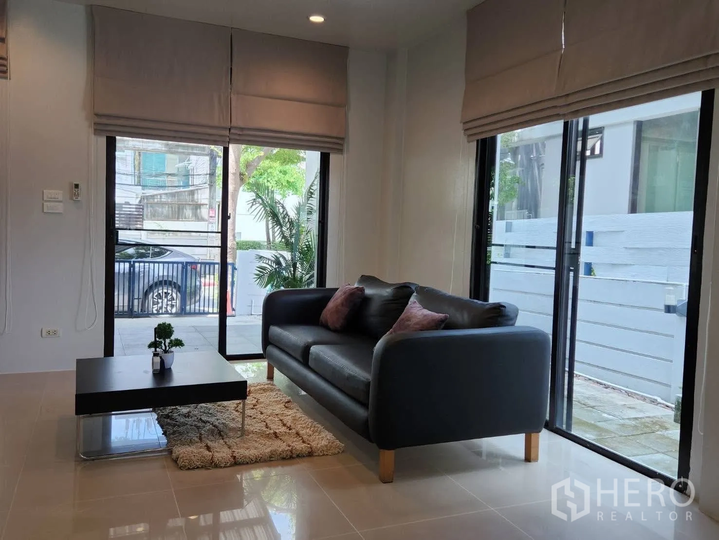 Townhouse for rent in Suan Luang, Bangkok - Living area view toward the front gate through floor-to-ceiling glazing.