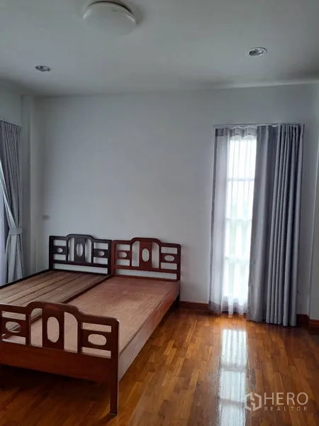 独立式住宅 出租在Prawet, Bangkok - 卧室配木床，实木地板与高窗帘窗户。