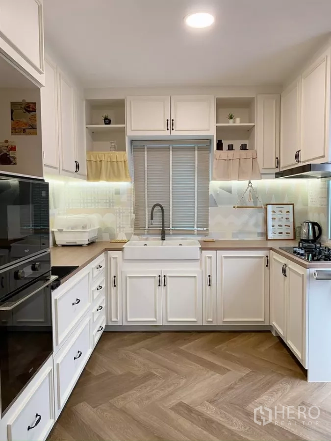 Detached House for sale in Sai Mai, Bangkok - U-shaped kitchen with farmhouse sink, white cabinets and under-cabinet lighting.