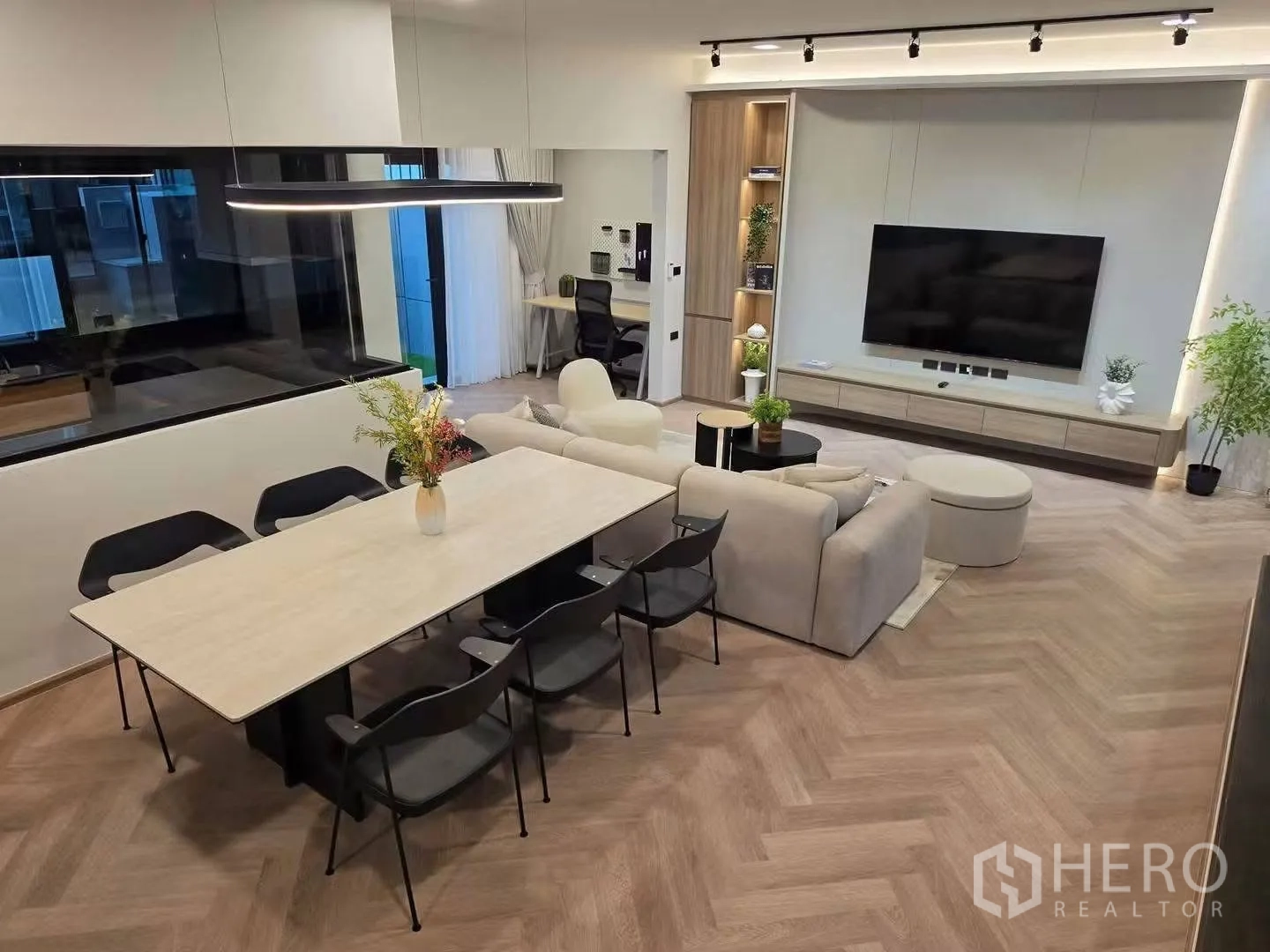 Townhouse for rent in Bang Phli, Samut Prakan - Open-plan living and dining area with herringbone floor, wall-mounted TV, and modern lighting.