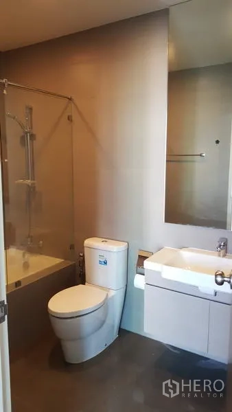 Condominium for rent in Phaya Thai, Bangkok - Modern bathroom with bathtub and shower screen, toilet, vanity and large mirror.