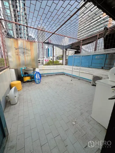 Shophouse for rent in Watthana, Bangkok - Rooftop terrace with tiled floor and metal lattice overlooking the city skyline.
