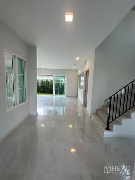 Detached House for rent - Hallway view across the ground floor toward the garden with staircase and sliding doors.
