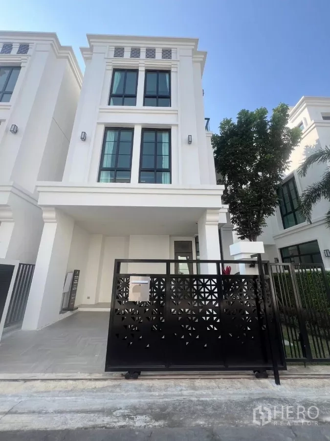 独立式住宅 出租在Lat Phrao, Bangkok - 三层独栋住宅外立面，白色现代设计，黑色滑动大门与高窗