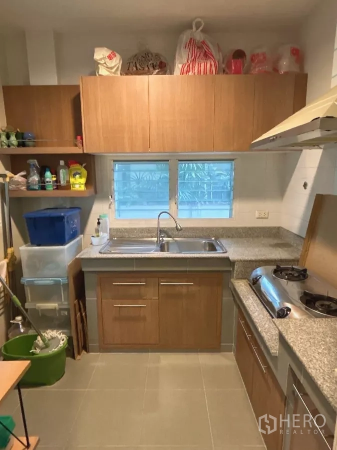 Detached House for sale in Bang Kapi, Bangkok - Separate Thai kitchen with granite counters, double sink, and wood cabinetry.
