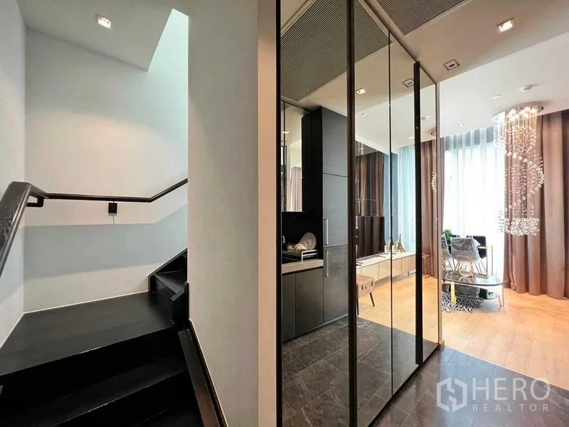 Condominium for rent - Entrance corridor showing staircase to mezzanine and compact kitchen with mirrored doors.