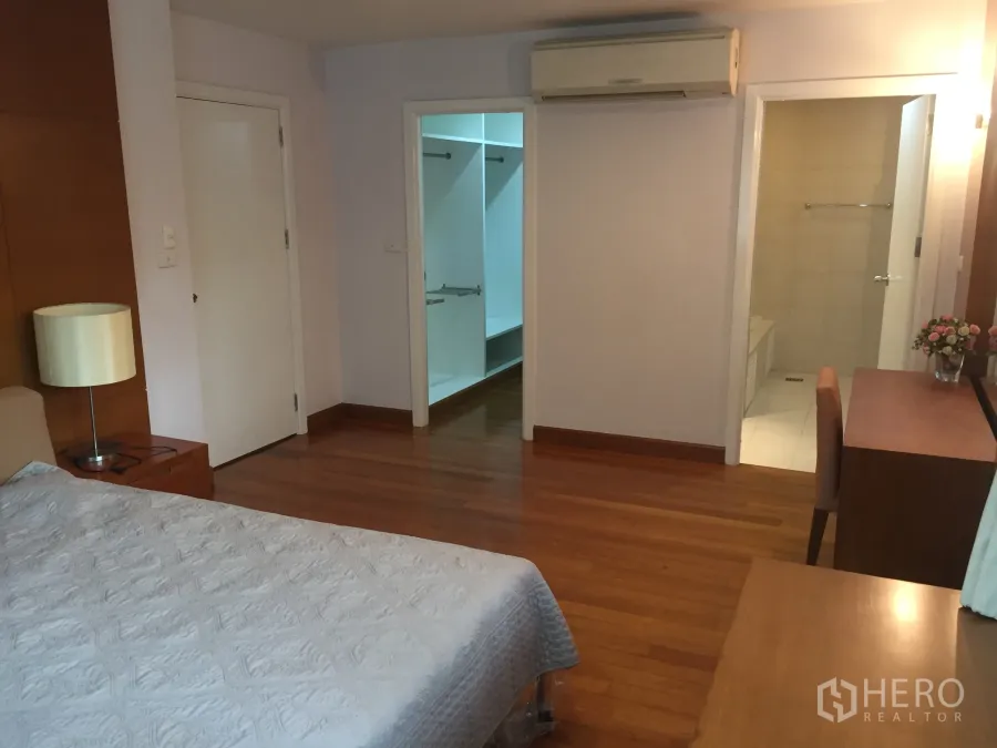 Detached House for rent in Watthana, Bangkok - Master bedroom with wooden flooring, air conditioning, walk-in closet and ensuite bathroom.
