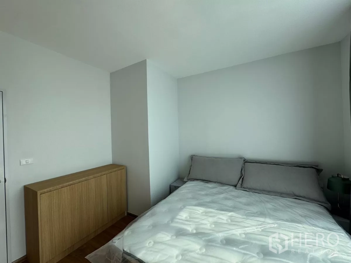 Townhouse for rent in Bang Phli, Samut Prakan - Master bedroom angle showing bed and low wood cabinet beside the window.