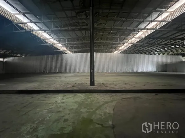 Factory for rent in Bang Pakong, Chachoengsao - Expansive factory floor with central columns and natural light strips along the roof.