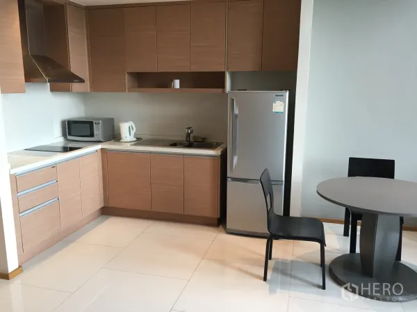 公寓 出租在Khlong Toei, Bangkok - 现代L型厨房，木质柜体、灶台、微波炉与小餐桌
