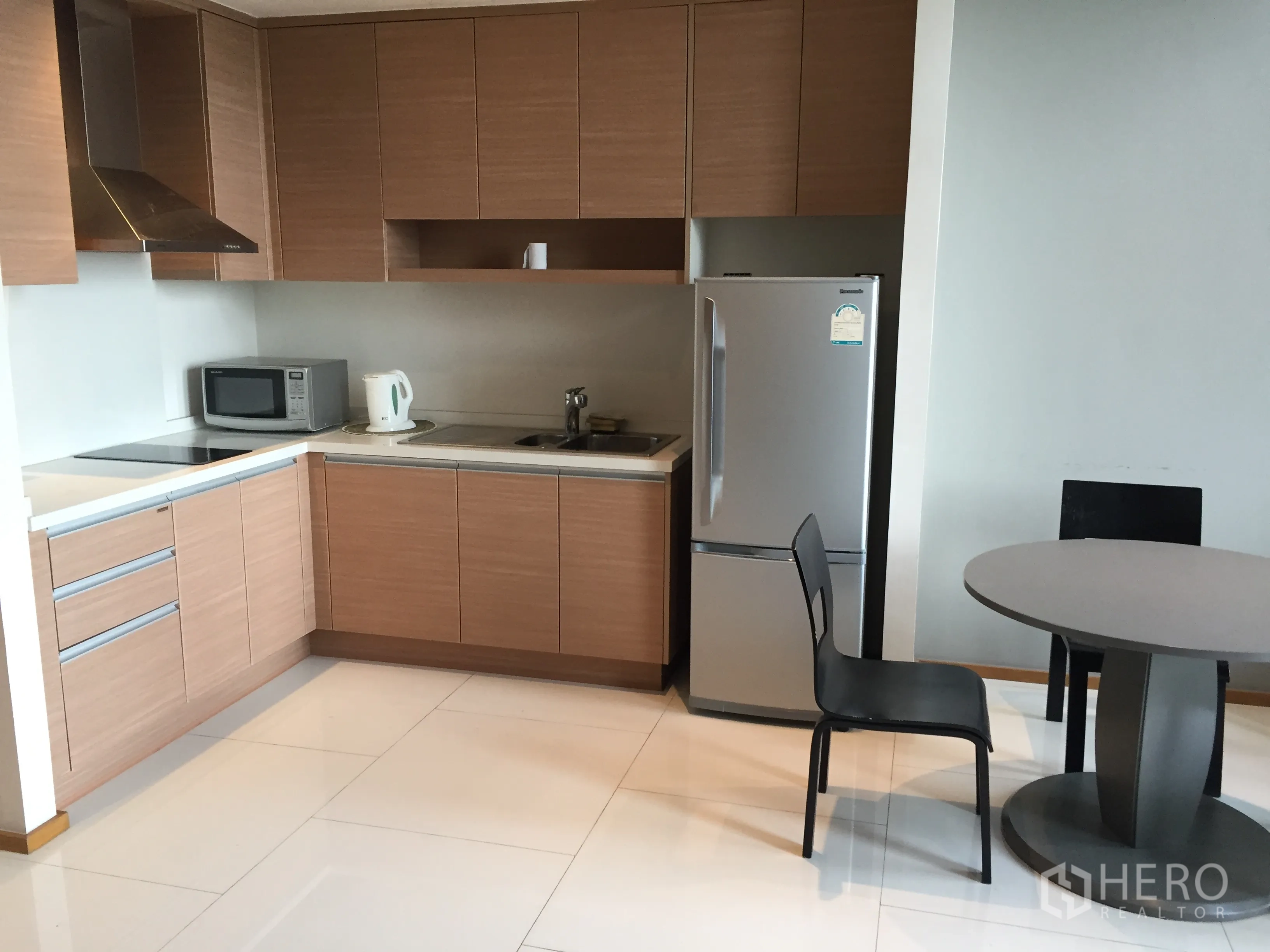 公寓 出租在Khlong Toei, Bangkok - 现代L型厨房，木质柜体、灶台、微波炉与小餐桌