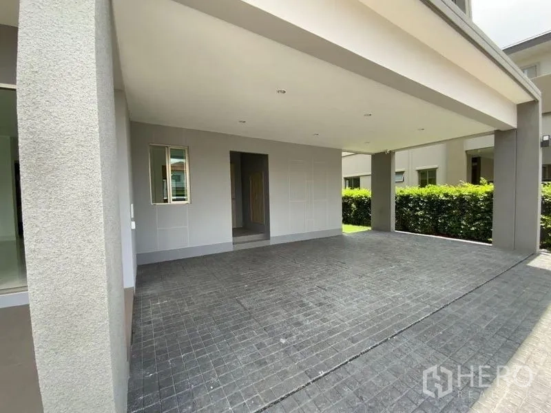 Townhouse for rent in Prawet, Bangkok - Covered two-car carport with tiled driveway beside the main entrance.