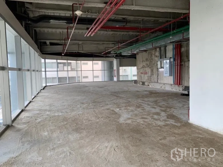 零售空间 出租 - 转角商铺，环幕式玻璃采光，裸露管线与未完成的混凝土地面。