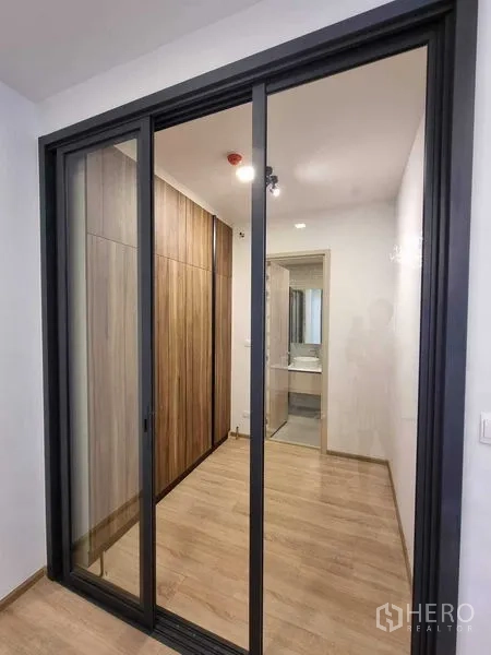 Condominium for rent in Ratchathewi, Bangkok - Sliding glass door to corridor with wood wardrobe and bathroom beyond.