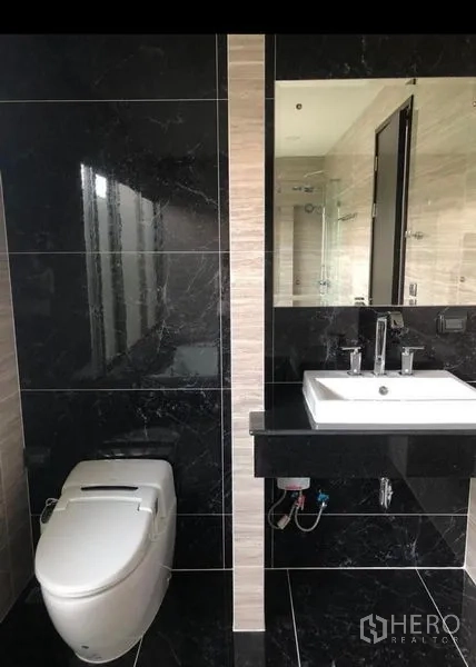 独立式住宅 出租在Lat Krabang, Bangkok - 黑色大理石墙面的浴室，台上盆与坐厕。