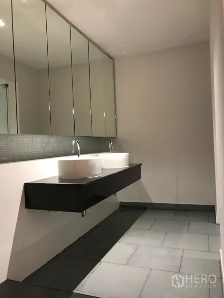 Condominium for rent in Khlong Toei, Bangkok - Modern bathroom with long floating vanity, twin vessel sinks and mirrored cabinets.
