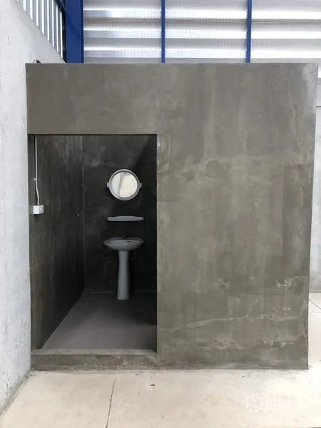 Factory for rent in Lat Lum Kaeo, Pathum Thani - Simple industrial restroom with pedestal sink and mirror in a concrete cubicle.