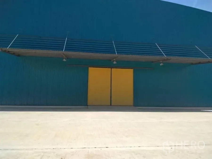 Factory for rent in Mueang Samut Prakan, Samut Prakan - Factory exterior with teal cladding, large yellow sliding doors, canopy and concrete apron.