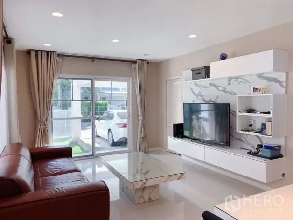 บ้าน ให้เช่าหรือขายในBang Phli, Samut Prakan - ห้องนั่งเล่นมองออกสู่ประตูบานเลื่อนและลานจอดรถ พร้อมสนามหญ้าเล็ก