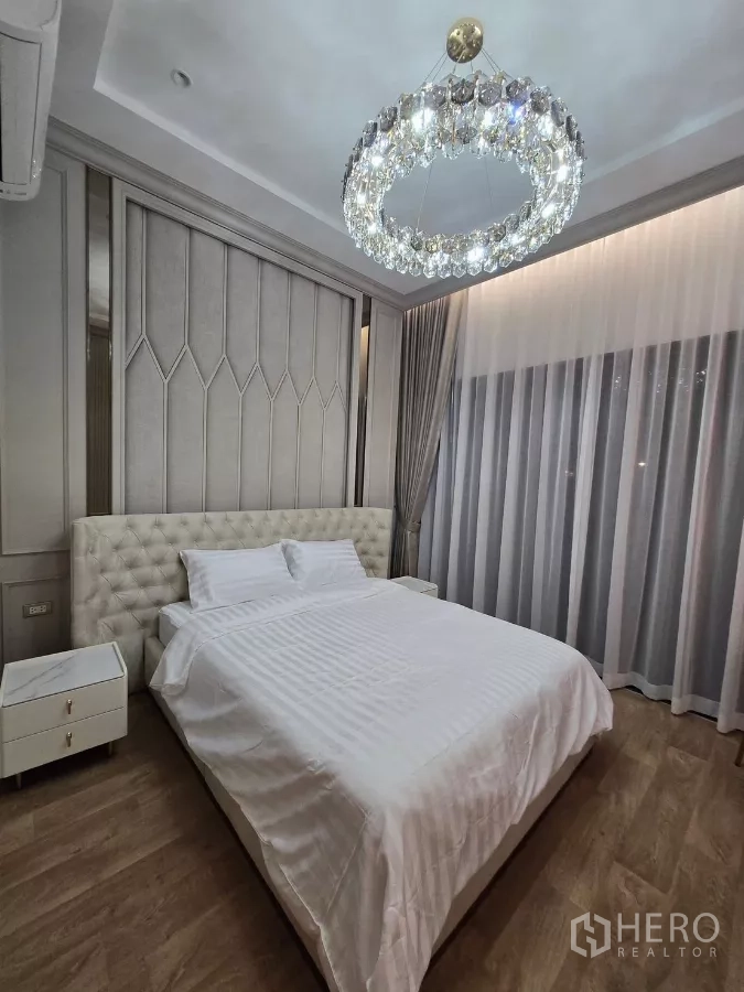 Detached House for rent or sale in Bang Kapi, Bangkok - Bedroom with padded headboard, wood flooring and a circular crystal chandelier.
