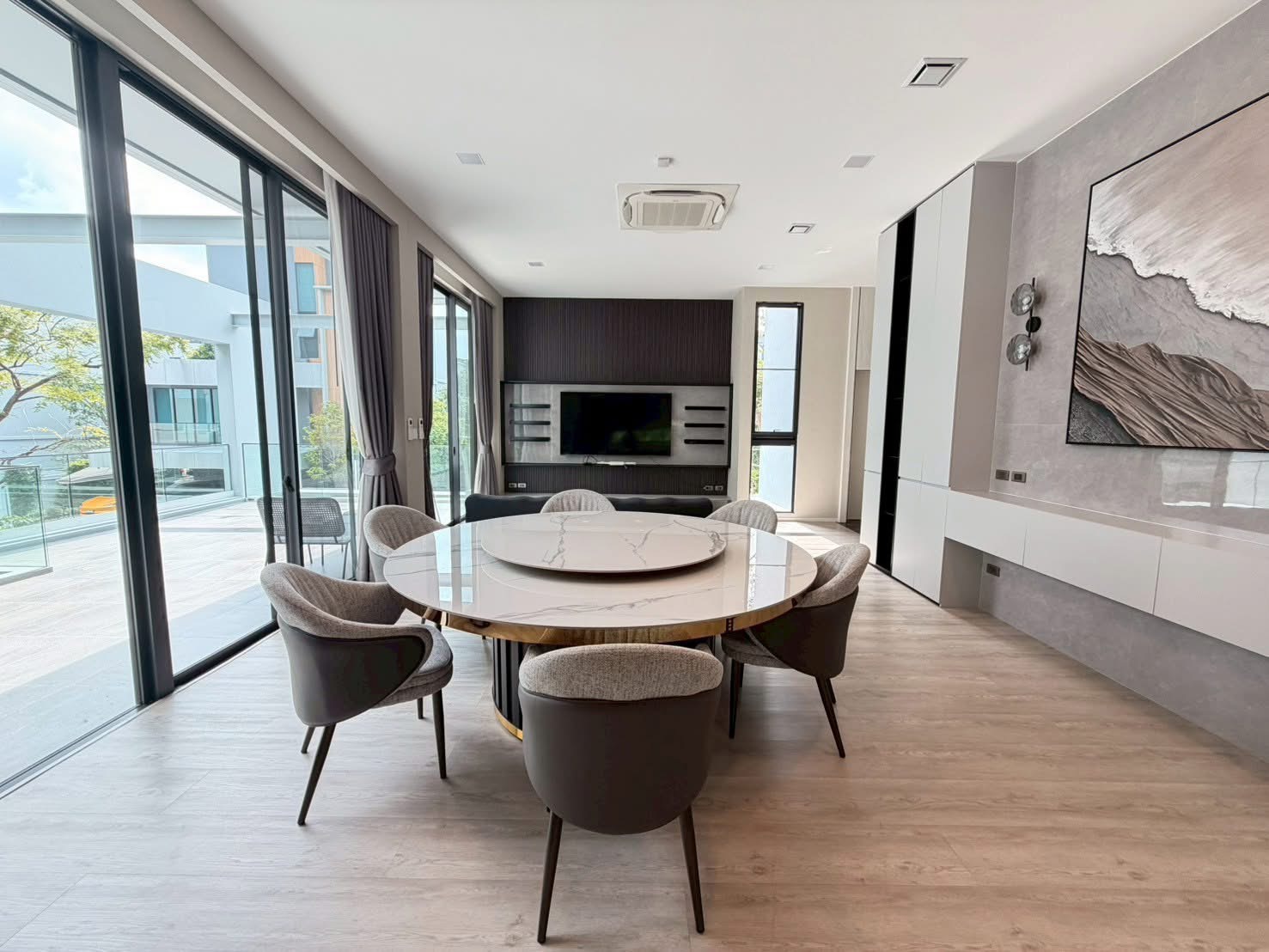 Detached House for rent in Saphan Sung, Bangkok - Open-plan living and dining room featuring a round marble table, TV wall and wide balcony access.