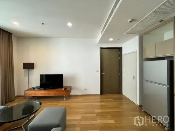 公寓 出租在Khlong Toei, Bangkok - 明亮客厅，木地板，低矮电视柜与落地灯，连接开放式厨房。