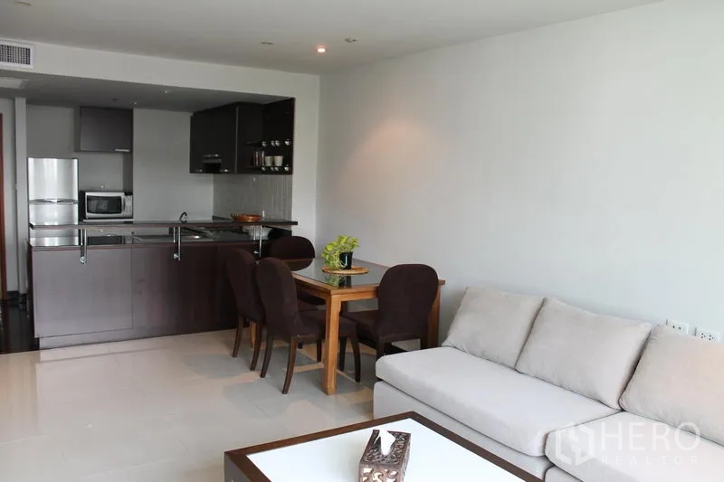 Apartment for rent in Bang Rak, Bangkok - Open-plan living room with sofa, dining set and a breakfast-bar kitchen.