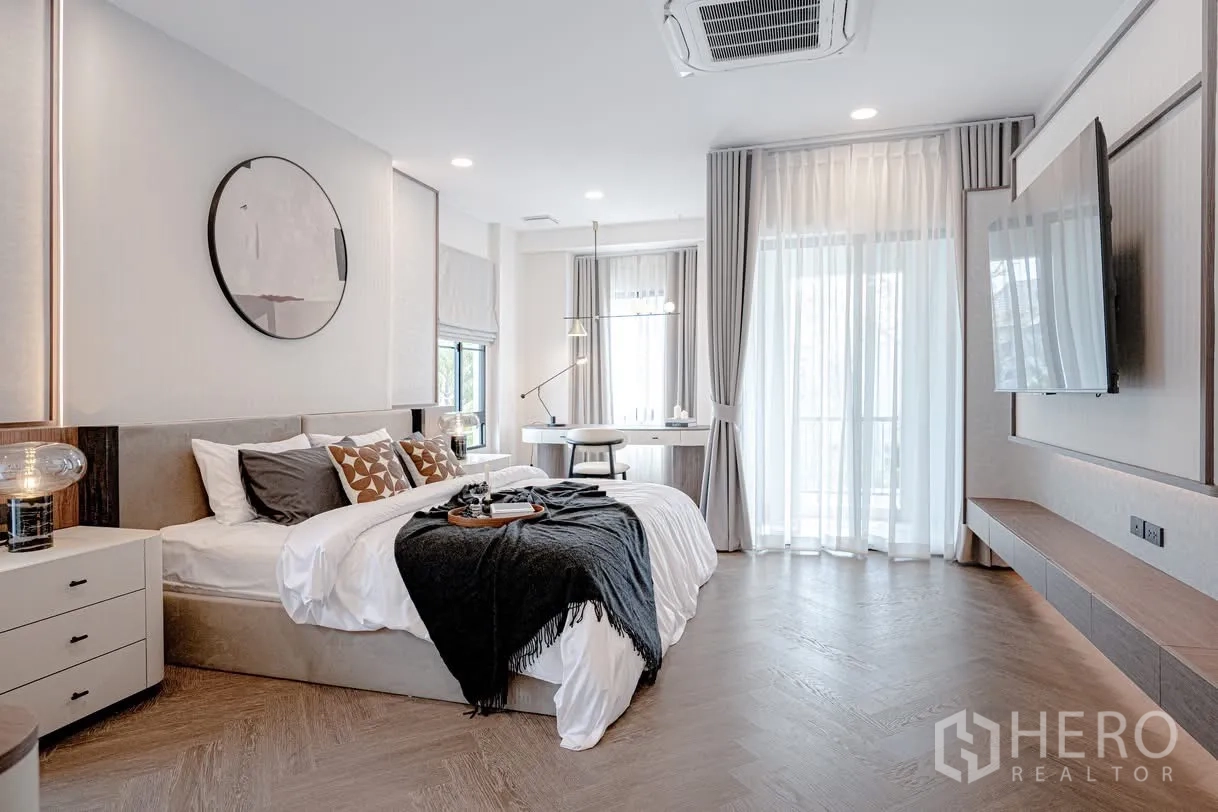 Detached House for rent in Saphan Sung, Bangkok - Spacious bedroom with large windows, sheer curtains, desk area, and ceiling cassette air-con.
