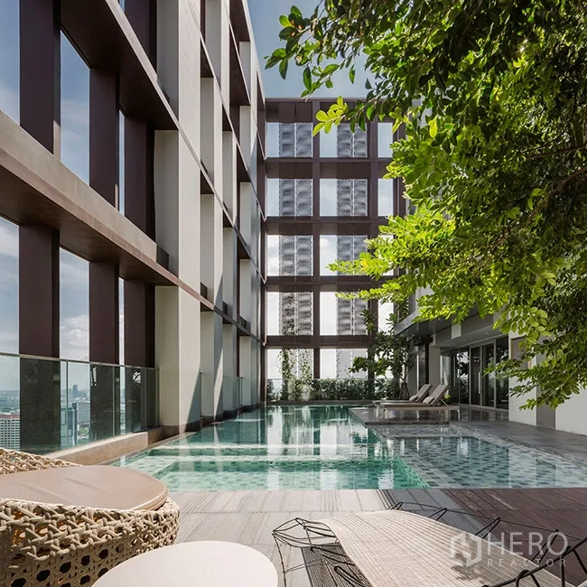 Condominium for rent in Khlong Toei, Bangkok - Rooftop swimming pool with sun deck and city views at the condominium.