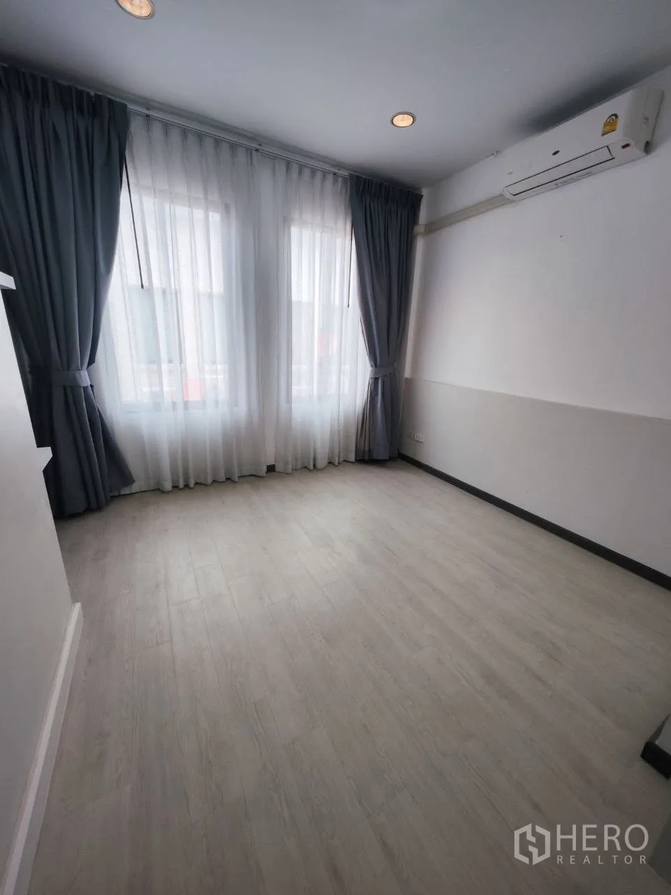 Home Office for rent in Bang Na, Bangkok - Empty room with large windows, curtains, air conditioner and wood floor.