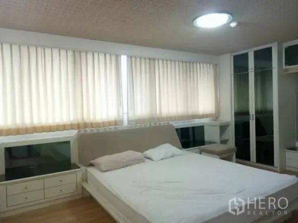 公寓 出租在Watthana, Bangkok - 主卧明亮，设大窗与米色窗帘，内置收纳与镜面衣柜，木质地板。