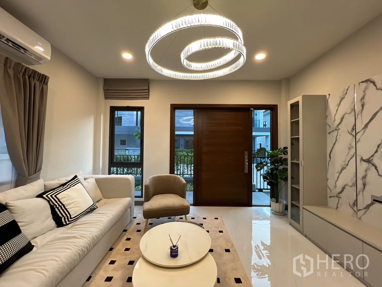 Detached House for rent in Bang Phli, Samut Prakan - Living area with statement ring chandelier, windows and built-in shelving.