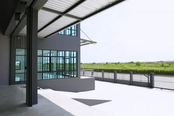 Factory for rent or sale in Bang Bo, Samut Prakan - Covered loading bay opening to a wide concrete yard with open green views.