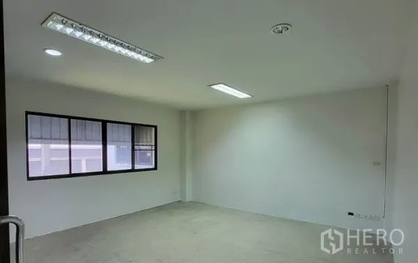 Warehouse for rent in Sam Phran, Nakhon Pathom - Empty office room with window and fluorescent ceiling lights inside the warehouse.