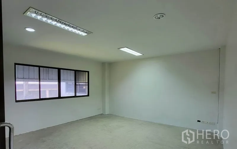Warehouse for rent in Sam Phran, Nakhon Pathom - Empty office room with window and fluorescent ceiling lights inside the warehouse.