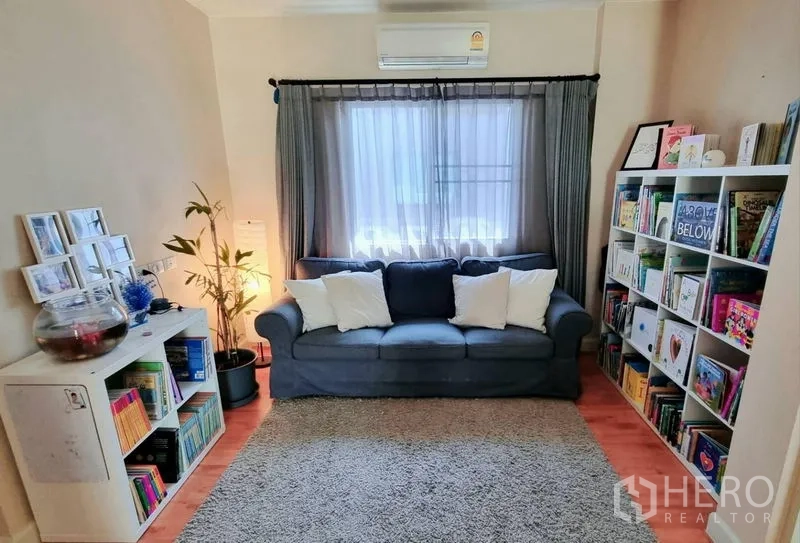 Detached House for rent or sale in Saphan Sung, Bangkok - Cozy reading nook with sofa, bookshelves and window drapes.